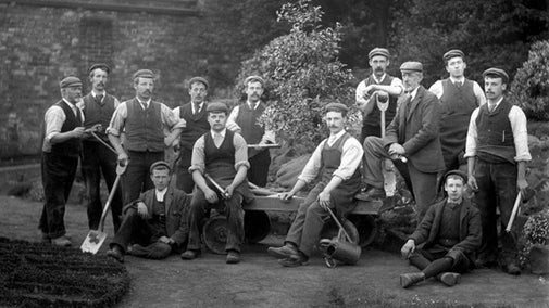 Historic photograph of the garden team, c.1897, showing thirteen men holding gardening equipment.